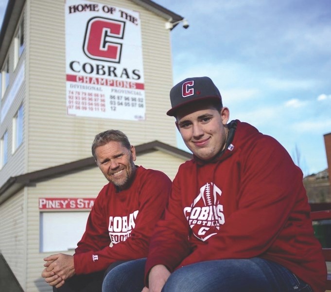 Cochrane High School football coach Rob McNab and player Cody Pickering sit out front of the school&#8217;s Vern Friesen field house Nov. 17. Pickering was taking equipment