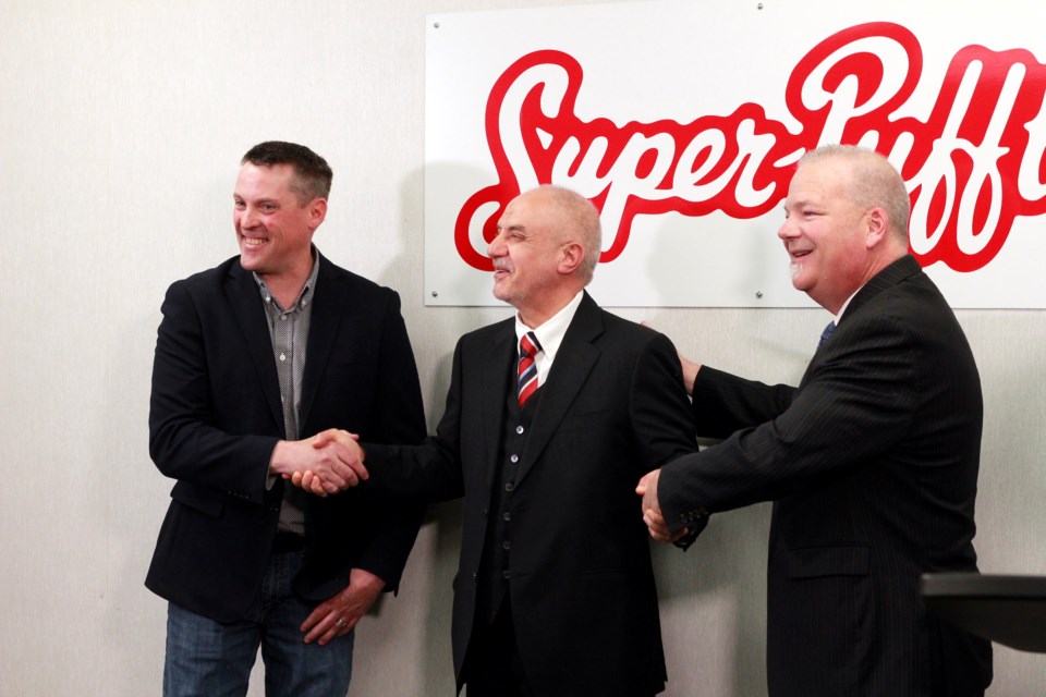 Nate Horner, Alberta Minister of Agriculture, Forestry and Rural Economic Development, Peter Brown, mayor of City of Airdrie, and Yousif Al-Ali, president and CEO of Super-Pufft Snacks Corp. shake hands at grand opening of Airdrie Super-Pufft multimillion dollar facility on May 17.
