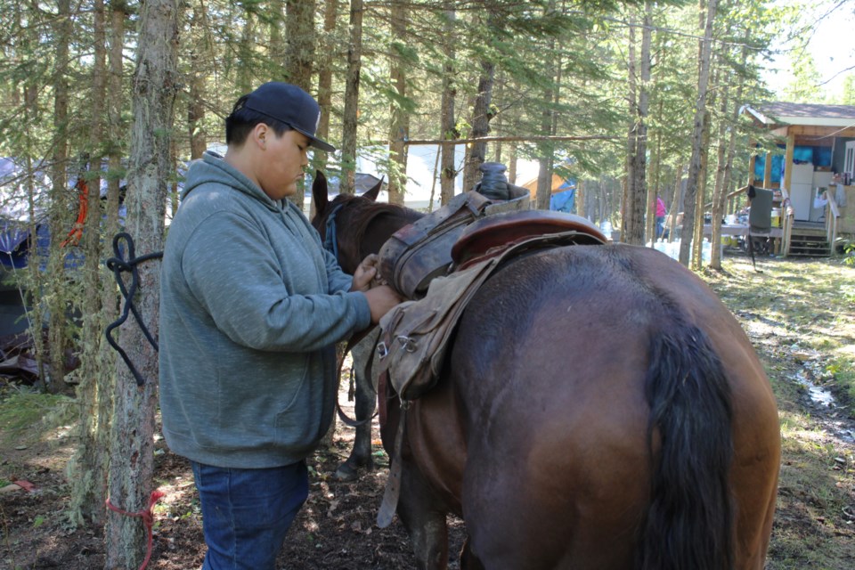 Ryder Achla, 16, saddles his horse ahead of a two-and-a-half hour trip back to the Halfway River First Nation from a weekend cultural camp.