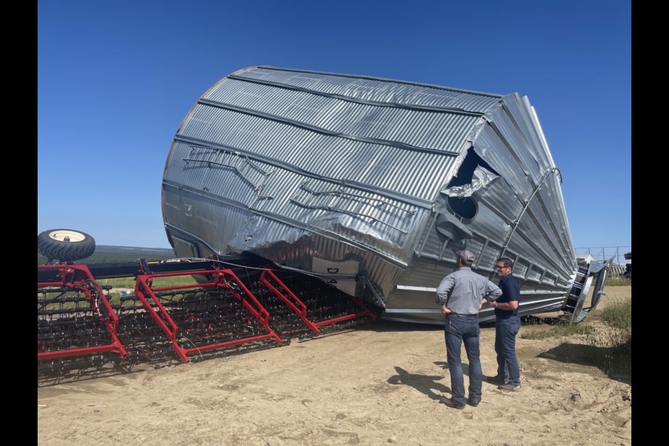 Farmer Ernie Wiebe shows MP Bob Zimmer one of the overturned grain bins. 