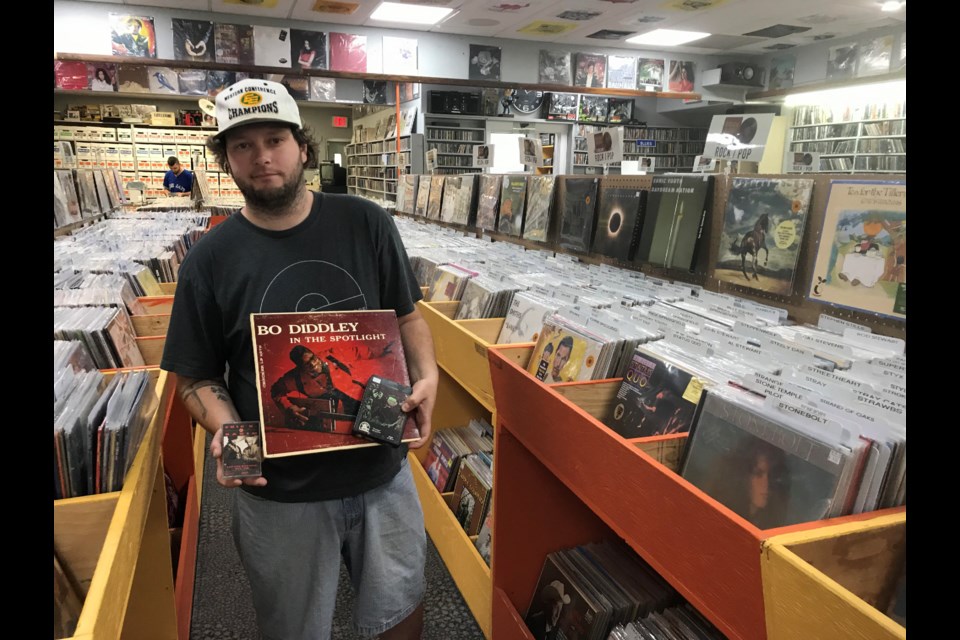 Ty Yakiwchuk displays a cassette tape, an eight-track tape and a vinyl LP inside Record Collector's Paradise in Edmonton. Photo: Gary Poignant
