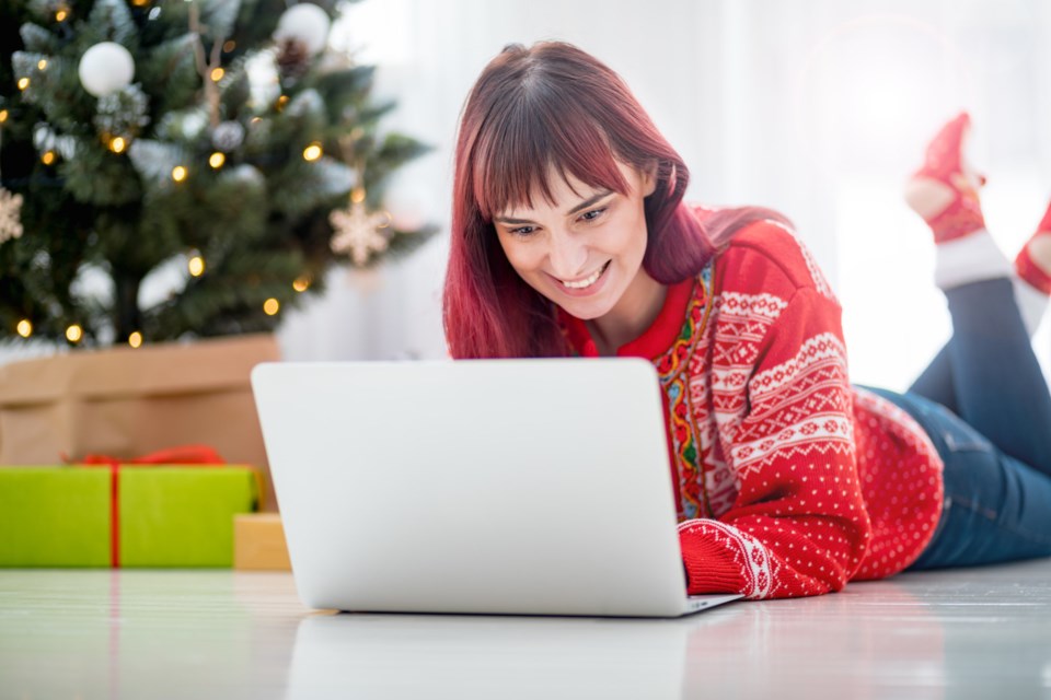 young-woman-using-laptop-next-to-xmas-tree-christm-8DKQYF4