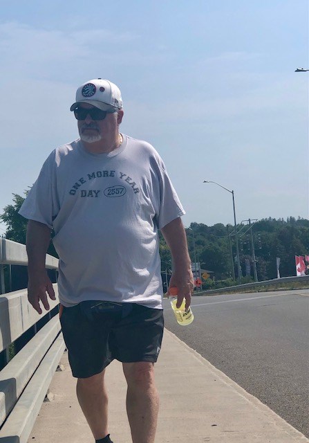 Lionel Strang walks over Highway 400 along St. Vincent Street on the last leg of his annual fundraising walk.