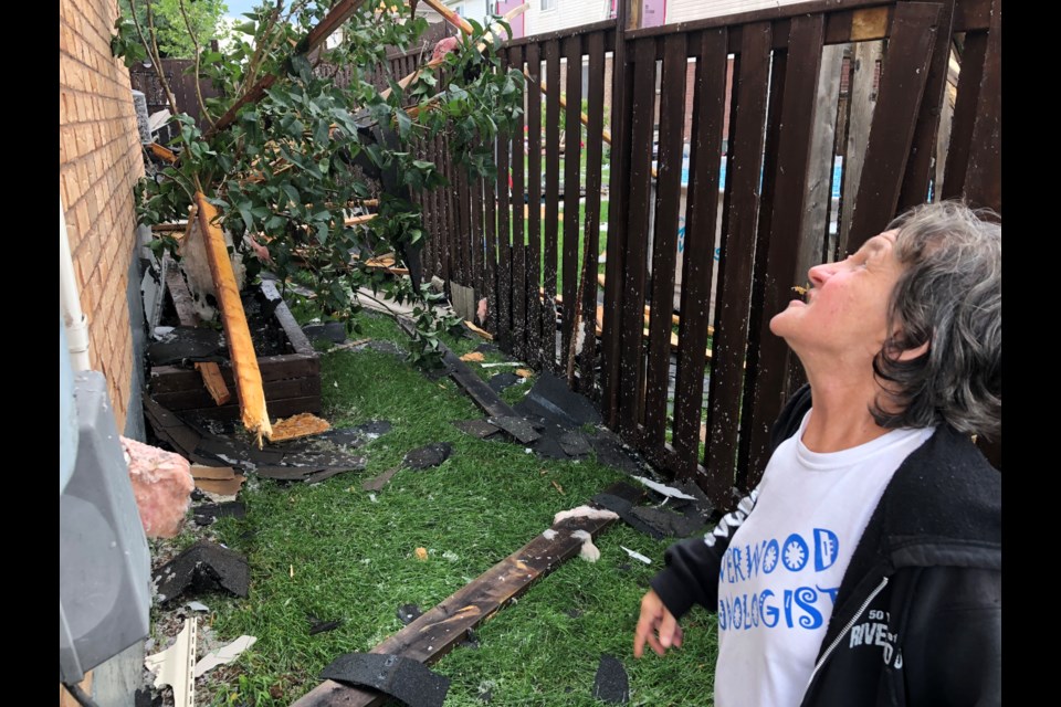 Lorie Rowland assesses the damage at the side of her house following Thursday's tornado.