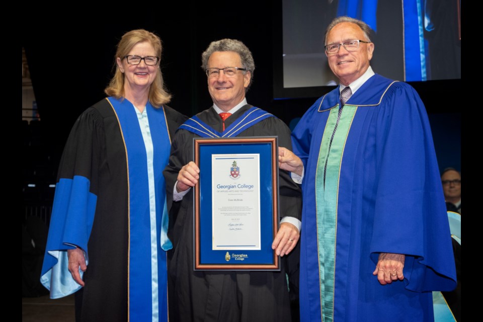Barrie business leader and philanthropist Tom McBride (centre) becomes the 17th person honoured with the Fellowship of Georgian College. The prestigious designation was conferred on McBride by Georgian College Board of Governors Chair Don Gordon and President and CEO MaryLynn West-Moynes during convocation ceremonies at the Barrie Molson Centre on June 19.  (Georgian College / Doug Crawford)