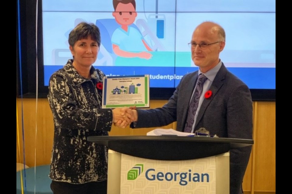 Dr. Charles Gardner presents Michele McConney, manager of athletics, with a 2019 Smoke-Free Champion Award for clearing the air at all seven Georgian College campuses so students and staff can breathe easy while they study, learn and work at the school.