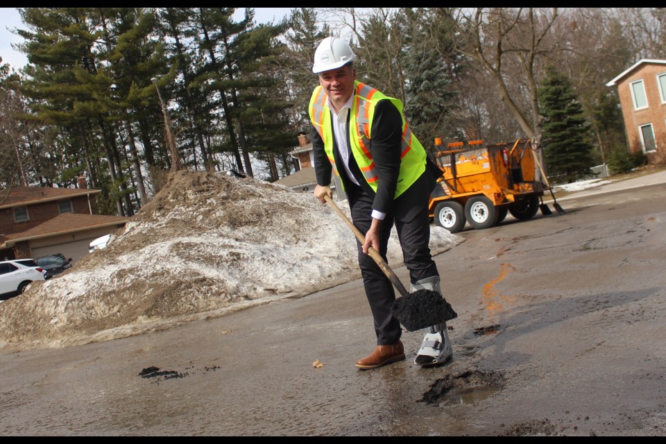 Barrie Mayor Alex Nuttall gets to work filling a pothole on Hailey Hollow in the city's northwest end, Thursday.