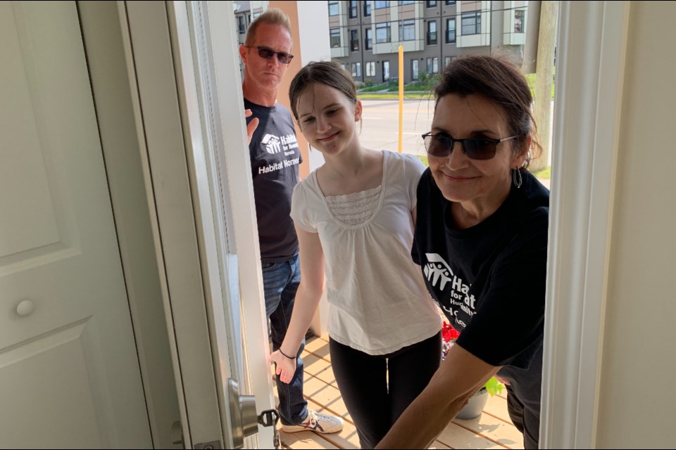 New Habitat for Humanity homeowners Angie Sumner, Stephen Hughes and their daughter Madison Sumner-Hughes unlock the front door to their new home. 