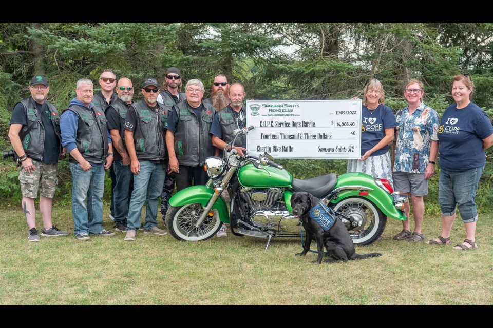 Members of the Samsara Saints Riding Club present a cheque for $14,000 to C.O.P.E. Service Dogs from their Aug. 13, 2022 charity Poker Run.