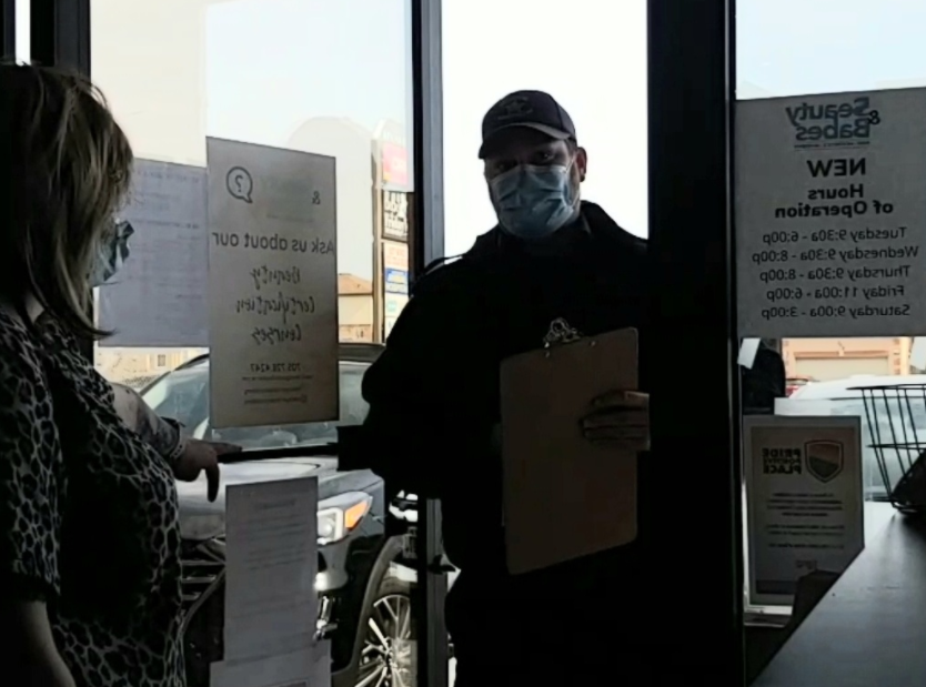A screenshot from Melissa Ferguson's Facebook Live video shows a city bylaw officer handing her a notice of violation for being open during provincial shutdown.