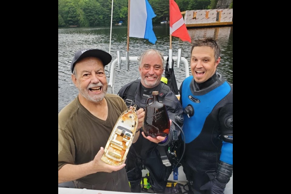 Dieter Mueller, Dave Davison and Adam Blokzyl, are ecstatic that the hunt for the lost case of whisky on Otter Lake ended in success. 