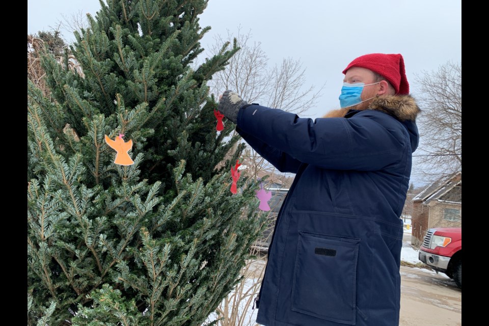 The Gilbert Centre's Silas Randell hangs an angel on the tree during a memorial service honouring the lives lost over the past year of those experiencing homelessness. 