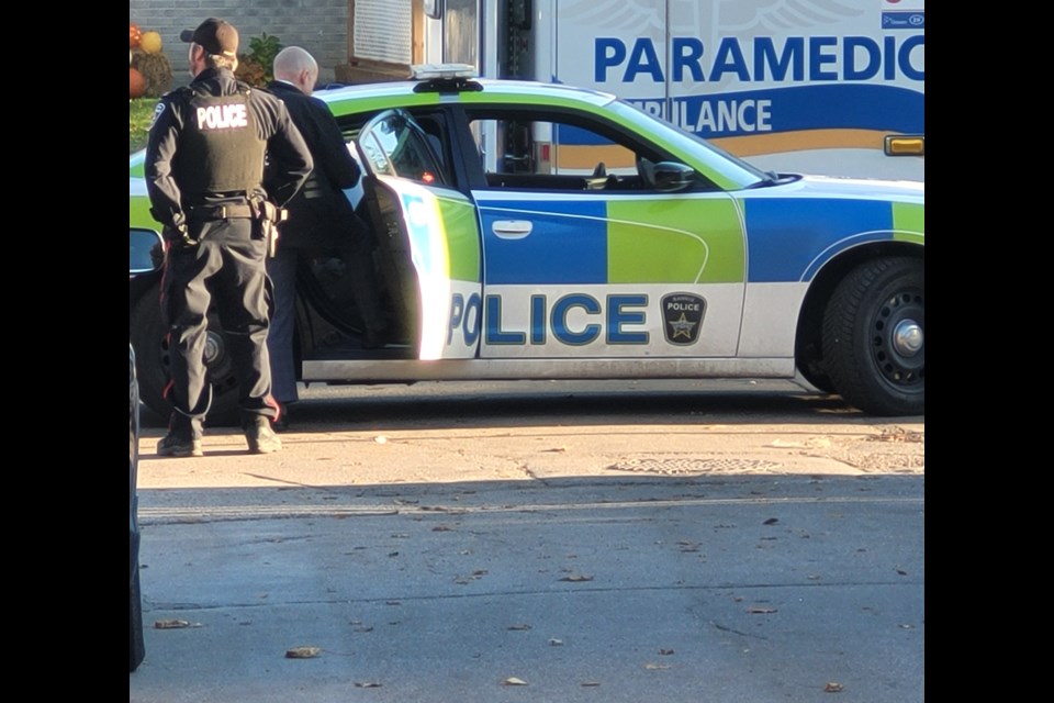 Investigators speak to someone in the back of a Barrie police car, Wednesday, Nov. 2, 2022.