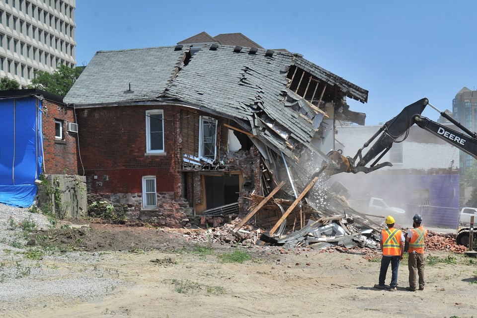 Workers watch as a Collier Street building near Owen Street is demolished Tuesday afternoon in preparation for a future seniors centre. Barrie City Hall can be seen at left. Ian McInroy for BarrieToday