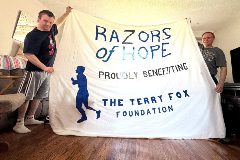 Jason Helmond and his father Ben shows off their banner for the sixth annual Razors of Hope event in support of the Terry Fox Foundation, on May 25 at Barrie police headquarters on Fairview Road in Barrie.