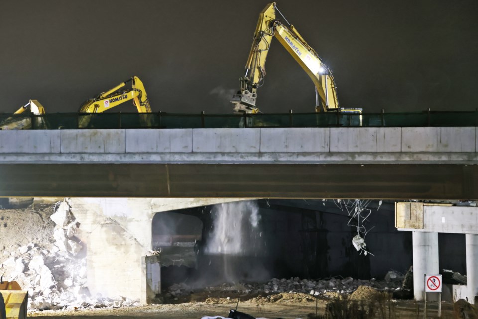 Debris falls as excavators armed with jack-hammer points demolish the existing Highway 400 bridge over Essa Road, after construction has been mostly completed on the new structures, on Saturday, Dec. 2, 2023