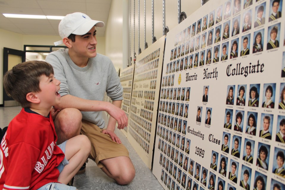 Six-year-old Finn Armatage and his 16-year-old brother, Walker, take a look at their father's graduation picture from 1991 at Barrie North Collegiate, Wednesday evening. Raymond Bowe/BarrieToday