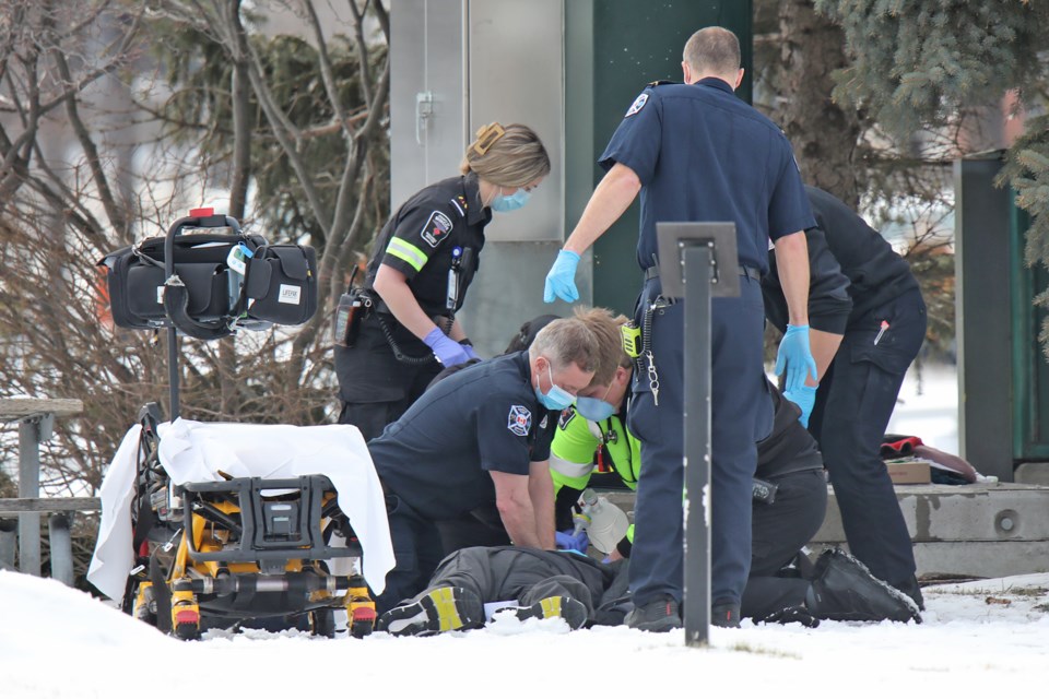 Emergency crews load a man onto a stretcher. He was found unconscious in Heritage Park on Sunday afternoon.