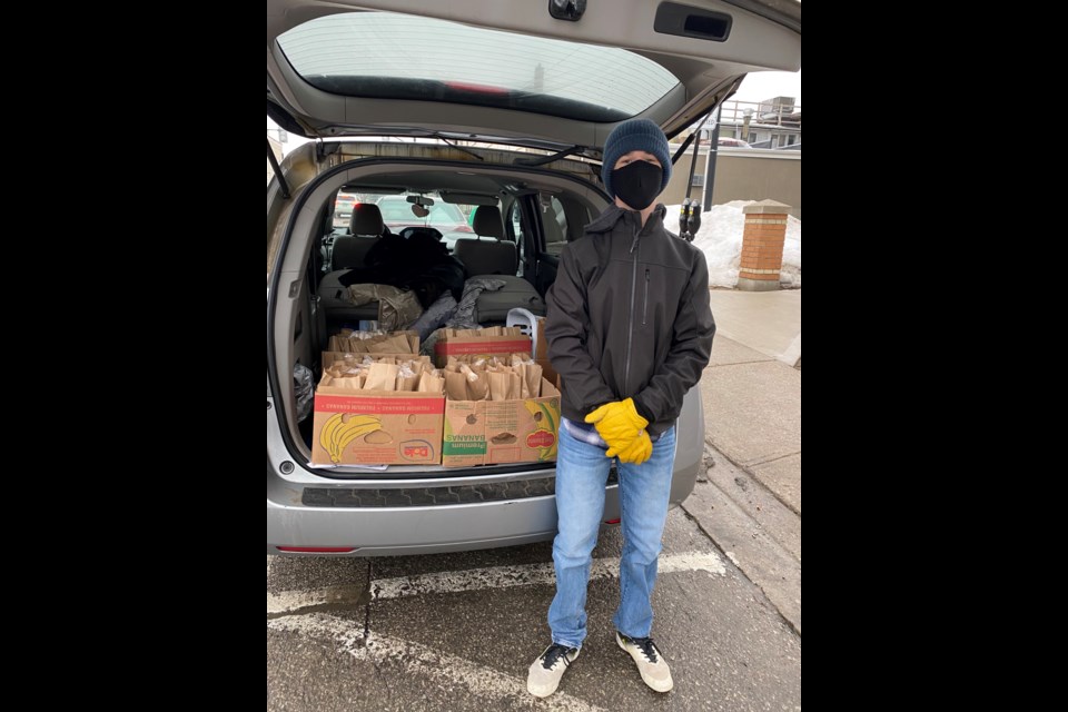 Enrique Mena stands beside the van that contains food and clothes for those experiencing homelessness in Barrie's downtown. 