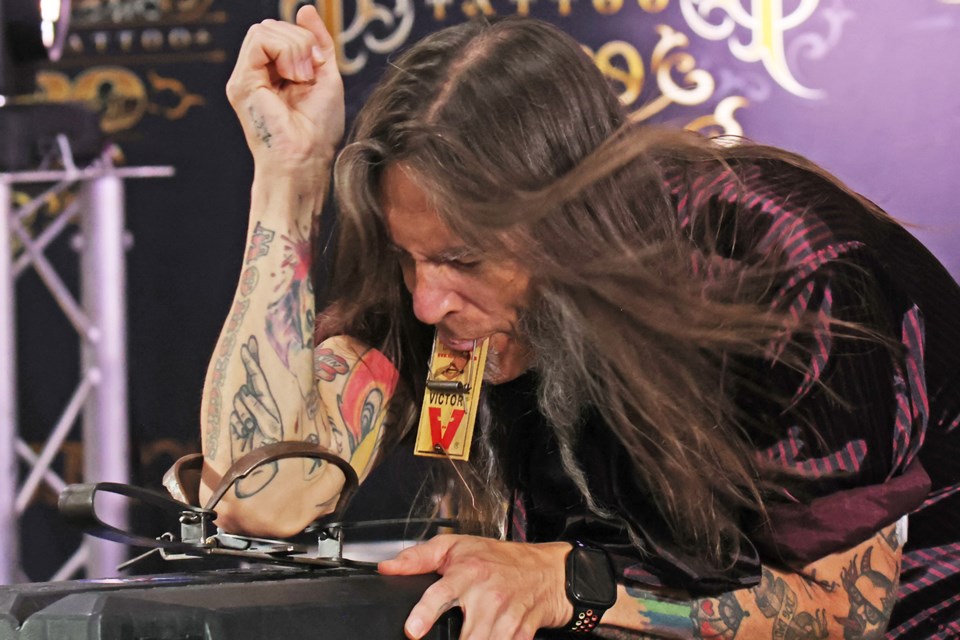 A man jams his arm into a leg trap after he stuck his tongue onto a mouse trap as performers entertain at the Inked Circus Tattoo Expo held at Eastview Arena in Barrie on May 25.