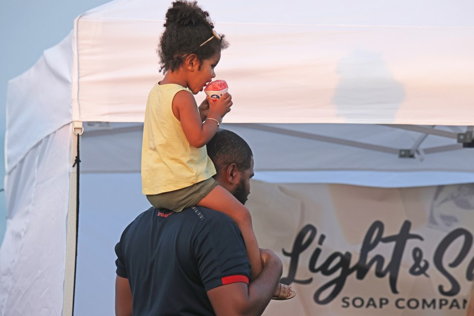 A young visitor stays occupied with a cold treat while her father shops for deals at Kempenfest in Barrie