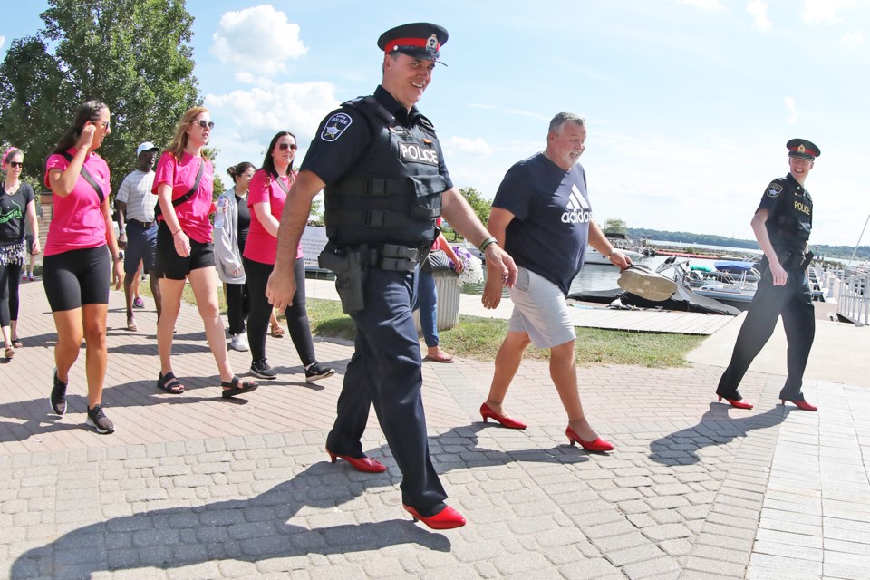 Coun. Robert Thomson, flanked by a pair of Barrie police officers, took part in the annual Walk a Mile in Her Shoes fundraiser at Heritage Park on Saturday in support of the Women and Children's Shelter of Barrie.