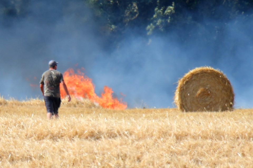 A farmer waits for fire crews to arrive during a grass fire in a farm field on the north side of Shore Acres Drive just east of Yonge Street in Innisfil at around 5 p.m.  Friday, July 20, 2018. Kevin Lamb for BarrieToday.