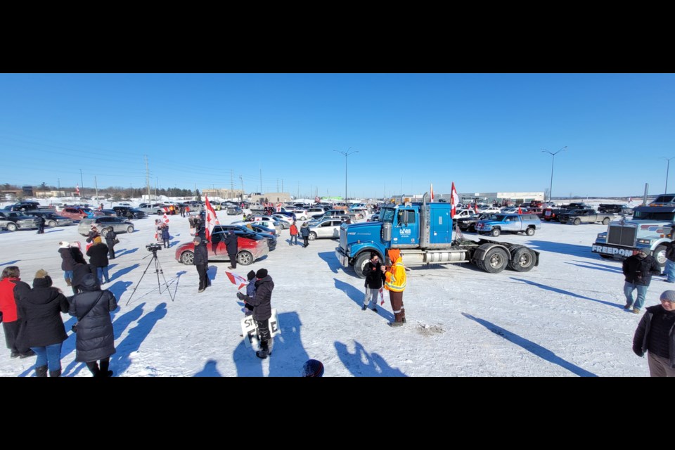 The view from a snowbank shows many cars and pickup trucks in the Sadlon Arena parking lot Saturday at a rally in support of Canadian truckers.