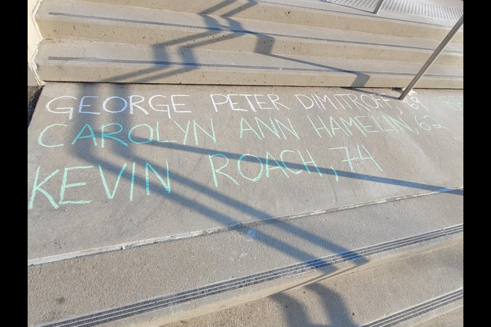 Names of those who have died of COVID-19 were written in chalk at Meridian Place in the early hours of Saturday by members of the community.