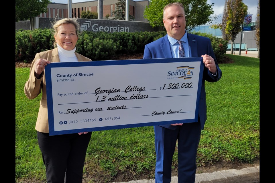 County of Simcoe Deputy Warden Lynn Dollin (left) and Georgian College president and CEO Kevin Weaver hold up a cheque representing the final installment from the county towards the Peter B. Moore Advanced Technology Centre, Thursday.