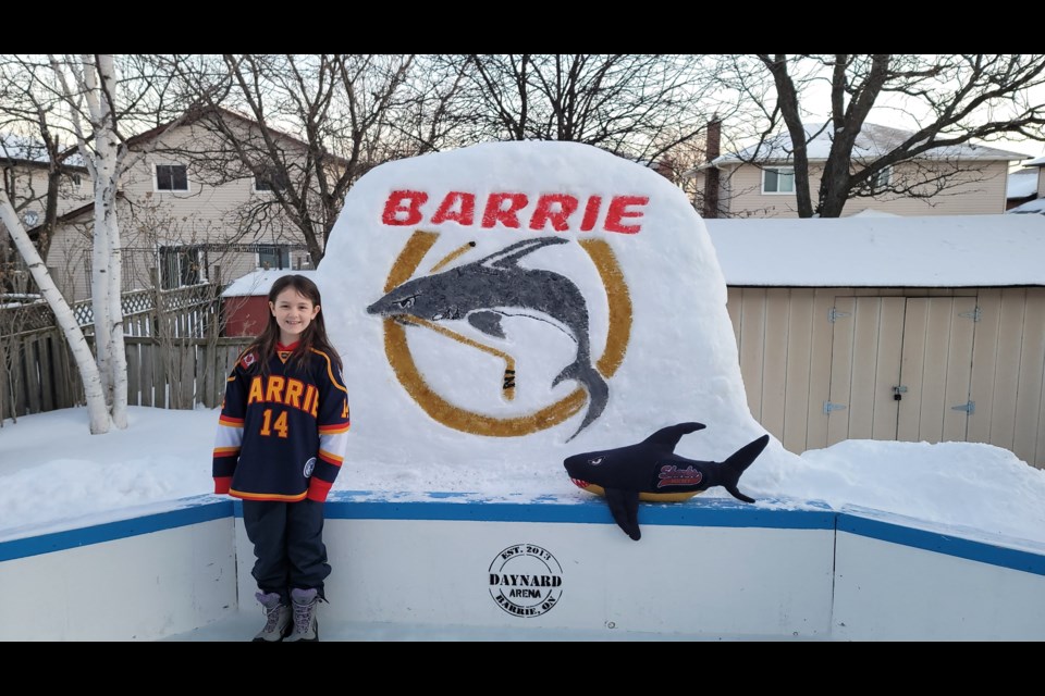 Wren Daynard is a proud U9 player with the Barrie Sharks and poses with the team logo, created by her dad, on the family's backyard rink.