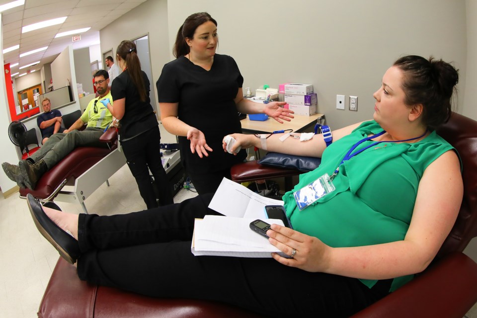 Nurse Amanda McNeil discusses the finer points of blood donation as CollingwoodToday reporter Jessica Owen donates blood for the first time at  Canadian Blood Services while Derek Kent looks on, and Logan Cosgrove waits his turn. Kevin Lamb for BarrieToday.