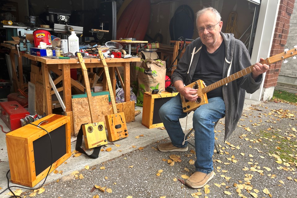 Barrie resident Dave McQueen, who has created homemade cigar-box guitars as a retirement activity, plays his electric guitar, which is plugged into an amplifier he has also made.
