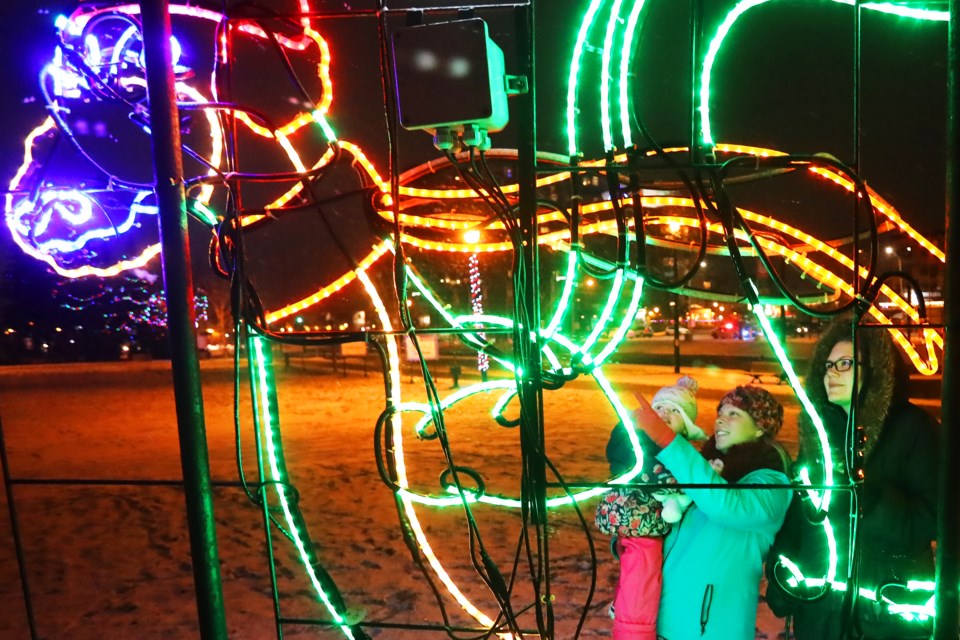 Rheanna Flear, left, Amanda Gilbert, and three-year-old Alaina Stanley check out the colourful lights of the Festival of Trees display along the waterfront in downtown Barrie on Sunday. Kevin Lamb for BarrieToday