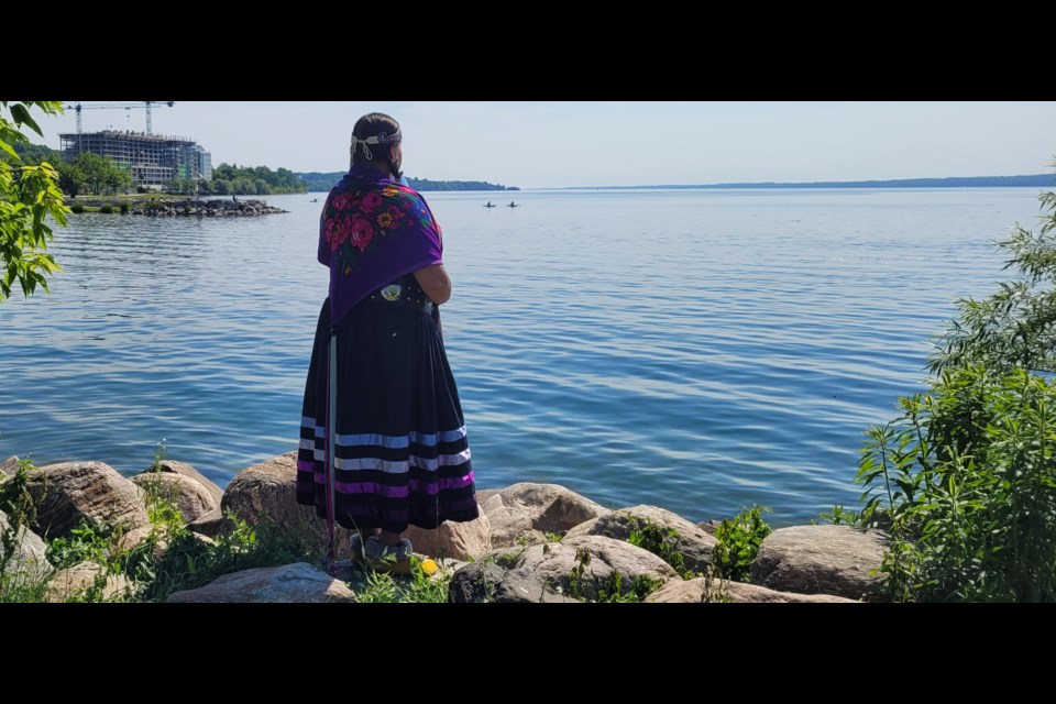 A regalia-adorned woman takes in the beauty of Kempenfelt Bay in Barrie on Tuesday, June 21.