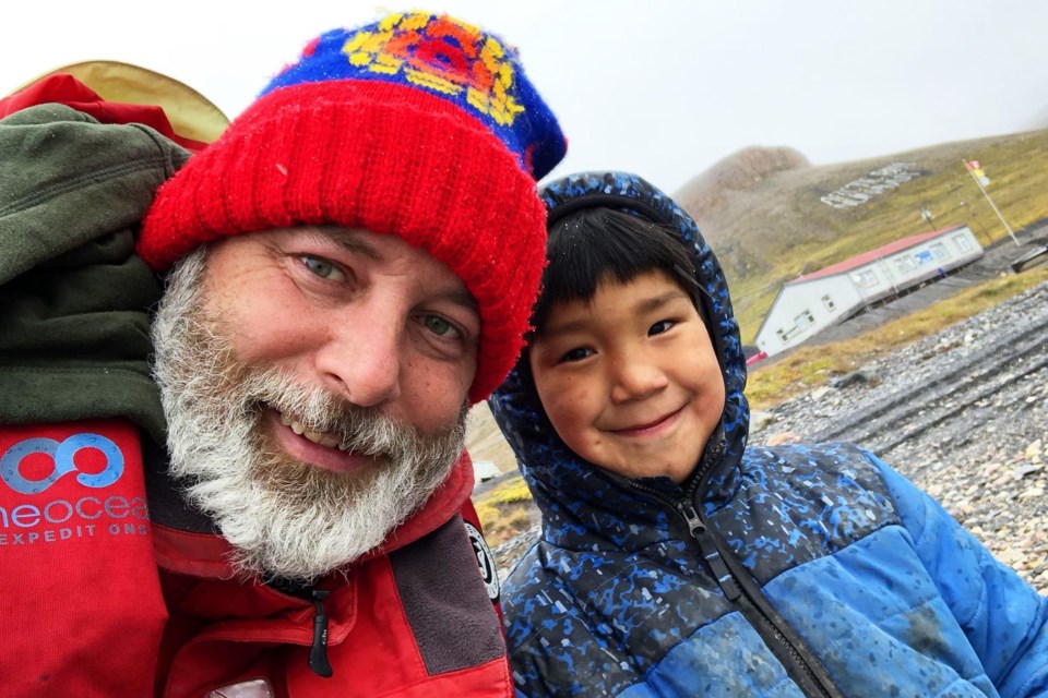 Photojournalist Kevin Lamb is greeted at the shoreline upon arrival by a young resident of Arctic Bay, Nunavut.