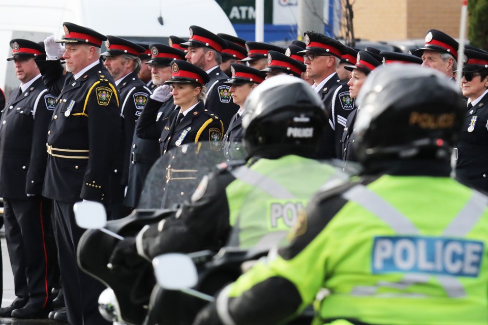 South Simcoe police officers line the street outside Sadlon Arena in south-end Barrie as a motorcycle escort leads the hearses on Bayview Drive during the final stretch of the funeral procession for the two slain South Simcoe police officers, Morgan Russell and Devon Northrup.