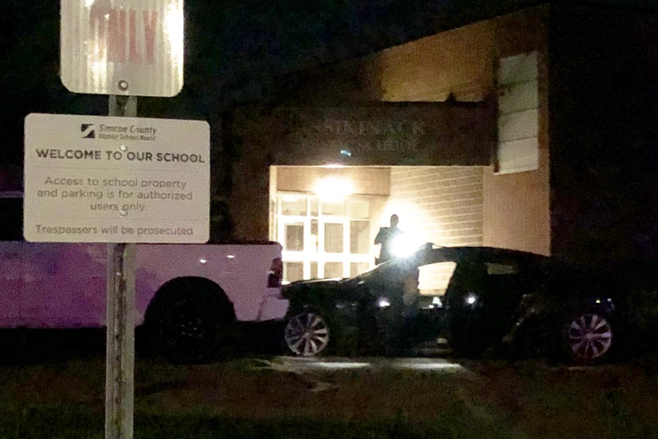 A police officer investigates the scene as a Tesla sits where it came to rest against a pickup truck in the parking lot of Assikinack Public School after it launched through the air when it jumped the steep railroad crossing on Little Avenue at 8:30 pm last night. Kevin Lamb for BarrieToday.