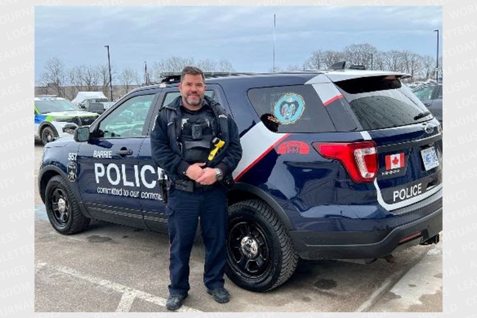 Barrie police Const. Jamie Westcott stands beside a police vehicle with a MMIWG decal. 