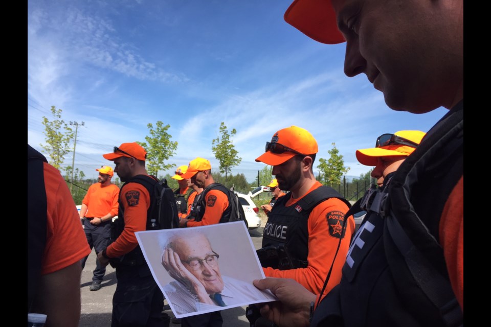 A Barrie Police officer looks at a handout photo of a fictitious missing senior who is the focus of a training exercise.  Sue Sgambati/BarrieToday