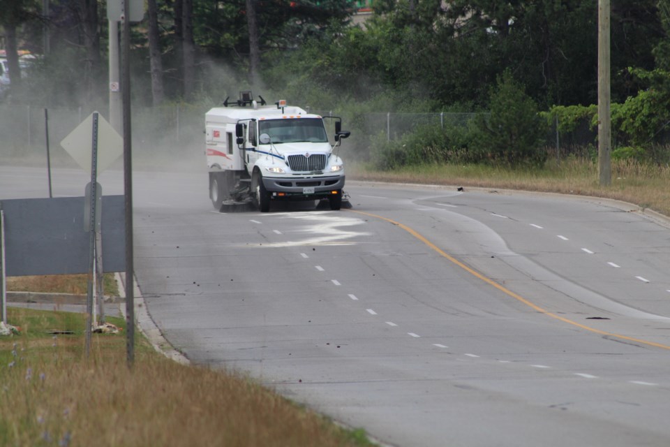 A city street sweeper cleans up fluids and debris off the road following a motorcycle crash, Monday morning on Fairview Road. Raymond Bowe/BarrieToday