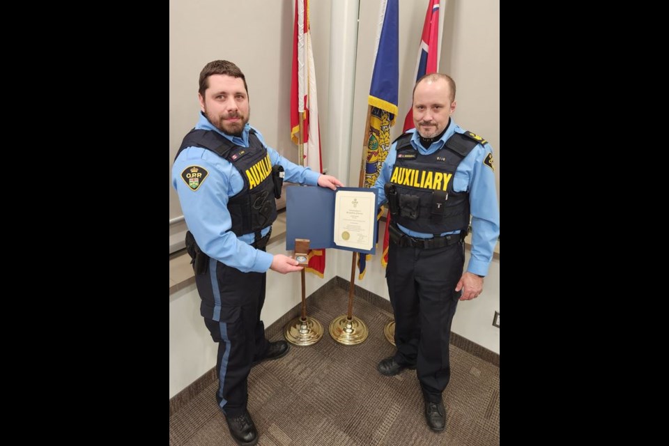 Nottawasaga OPP Auxiliary Staff Sergeant Andy McDougall presenting Auxiliary Constable Kyle Jones with a coin to celebrate 10 years of dedicated service to the auxiliary unit.