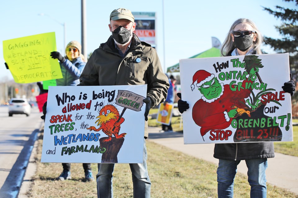 Protesters concerned about Bill 23's effects on the Greenbelt stand along Mapleview Drive outside of Barrie-Innisfil MPP Andrea Khanjin's constituency office on Saturday.