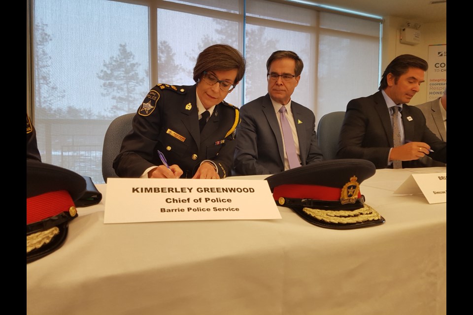 Barrie Police Chief Kimberley Greenwood signs the Police/School Board Protocol as SMCDSB director Brian Beal looks on. Shawn Gibson/BarrieToday