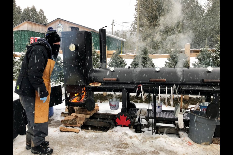 A barbecue cook feeds the wood stove feeding the smoker at Blue Mountain's hill-top outdoor eating area.