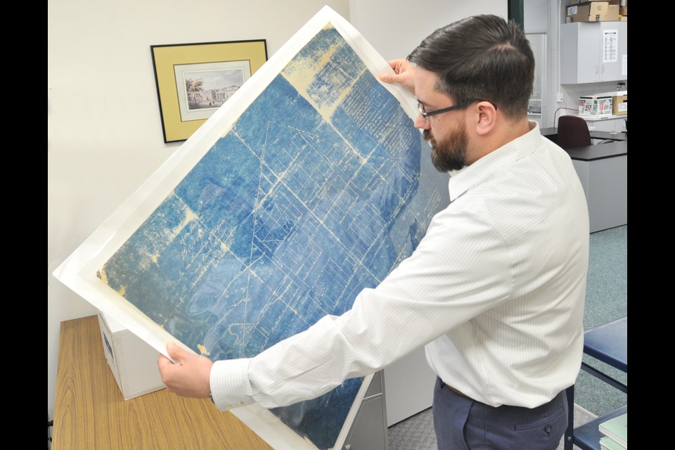 Archivist Matthew Fells, of the Simcoe County Archives, examines a copy of the 1833 Hawkins survey which laid out the first streets of Barrie. Ian McInroy for Barrie Today
