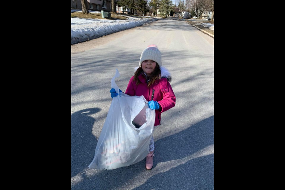 Five year old Natalie shows her strength and her community initiative by holding up the bag of garbage she and her mom and grandma collected around their street, Wednesday, March 18, 2020. Photo supplied 