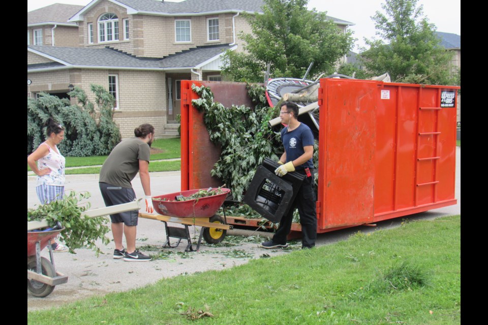 Ward 9 Councilor Sergio Morales helps load a bin with the debris left behind from the July 15 tornado that passed through Stunden Lane before doing even more damage down the road.                             