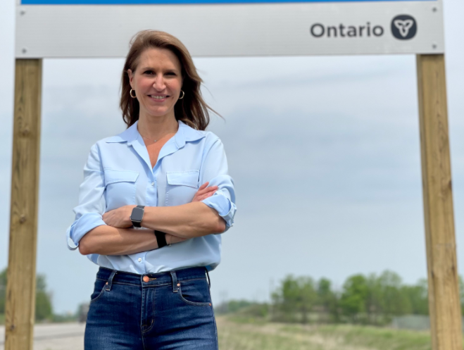 Minister of Transportation Caroline Mulroney in front of one of the new signs along the proposed route for the Bradford Bypass. 