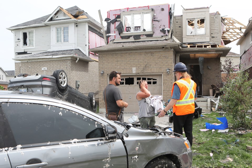 An insurance adjuster speaks to a family on Sun King Crescent about their damaged home a day after a tornado ripped through the south end of Barri. Kevin Lamb for BarrieToday.